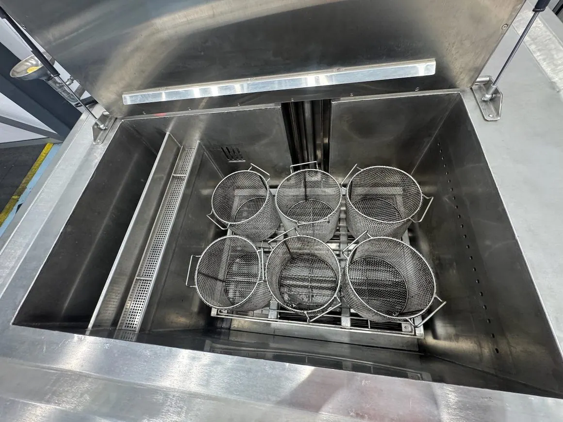 Baskets loaded with industrial parts going into an EVS 300 ultrasonic tank