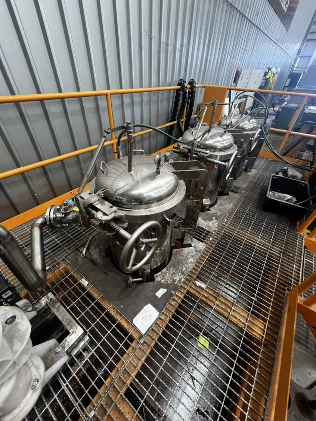 Three stainless filter housings in a row on the mezzanine, hoses and handwheel