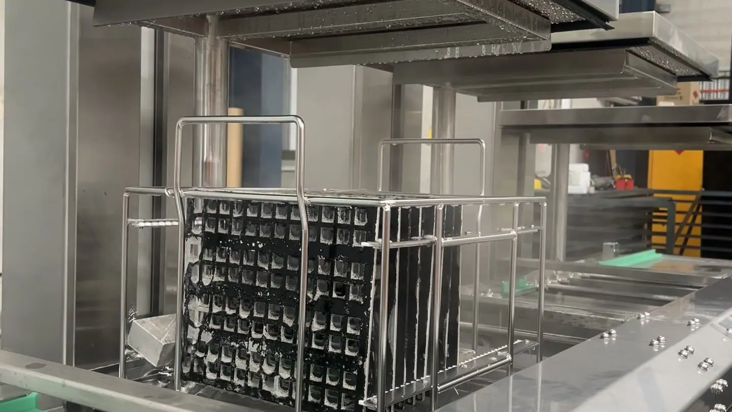 A rack of machined parts held above the ultrasonic wash tank of a Misonics Sono L-130 line