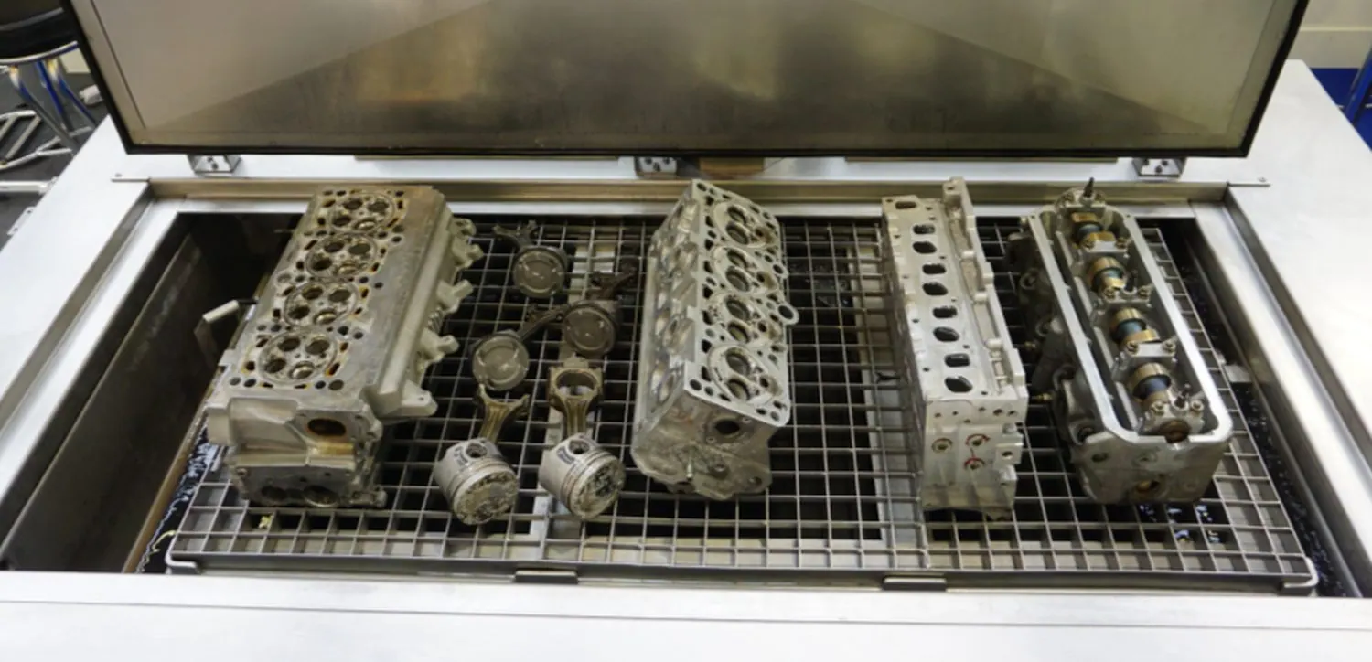 Cylinder heads, pistons and connecting rods loaded on the tray of an UltraTecno ACM ultrasonic cleaning machine